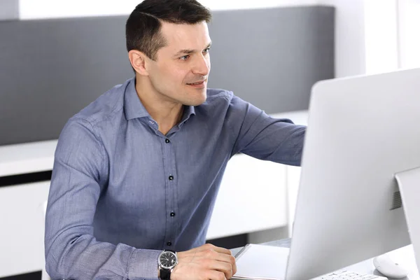 Businessman working with computer in modern office. Headshot of male entrepreneur or company director at workplace. Business concept
