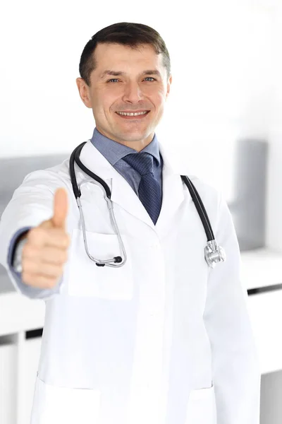 Arzt lächelt fröhlich in die Kamera, Daumen hoch. Perfekte medizinische Versorgung in der Klinik. Glückliche Zukunft in Medizin und Gesundheitswesen — Stockfoto