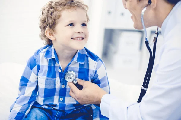 Orvos és türelmes gyermek. Orvos vizsgálja a kisfiút. Rendszeres orvosi látogatás a klinikán. Orvosi és egészségügyi ellátás fogalma — Stock Fotó