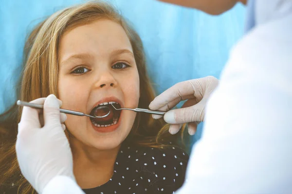 Menina sentada na cadeira dentária com a boca aberta durante o check-up oral, enquanto médico. Consulta ao dentista. Conceito de medicina. Foto tonificada — Fotografia de Stock