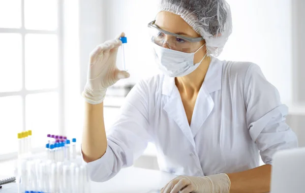 Koruyucu gözlüklü profesyonel kadın bilim adamı laboratuarda reaktörlerle araştırma tüpü kullanıyor. Tıp ve araştırma kavramları — Stok fotoğraf