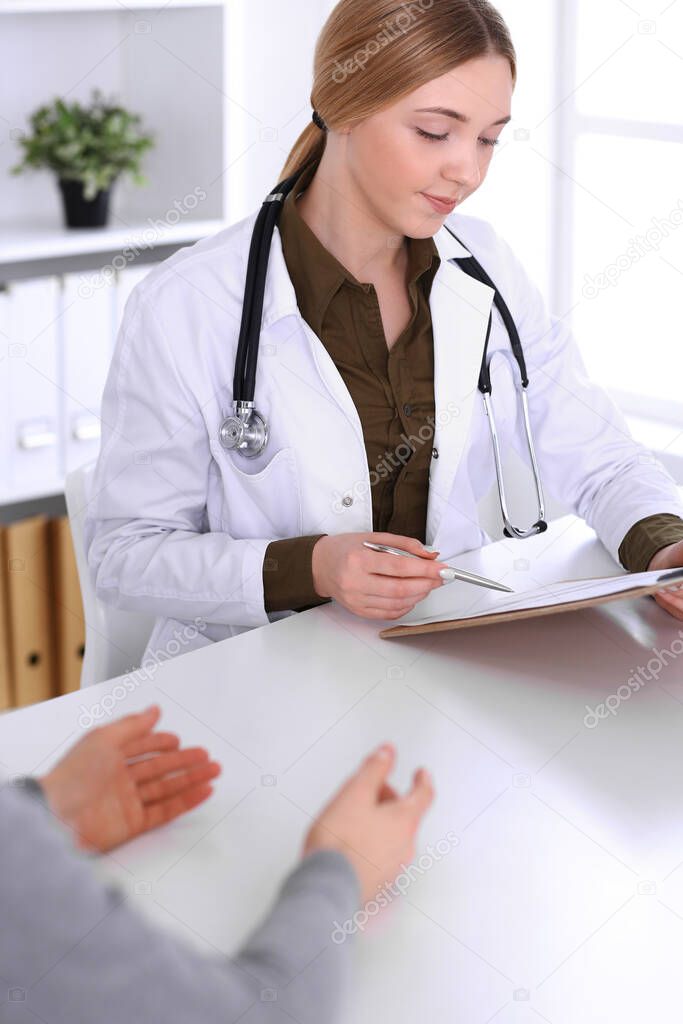 Young woman doctor and patient at medical examination in hospital office. Khaki colored blouse of therapist looks good. Medicine, healthcare and doctors appointment concept