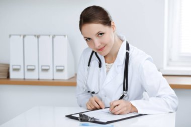 Kadın doktor klinikte oturuyor ve çalışıyor. Kadın doktor portresi. Tıp konsepti