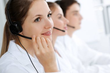 Merkezi ara. Güzel genç bir kadın müşterilere yardım etmek için kulaklık ve bilgisayar kullanıyor. İş konsepti