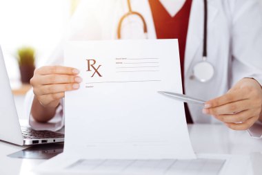 Bilinmeyen kadın doktor boş reçete formunu işaret ediyor. Yakın plan. Tıp konsepti