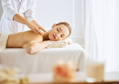 Güzel bir kadın kapalı gözlerle sırt masajından hoşlanıyor. Spa tedavisi kavramı