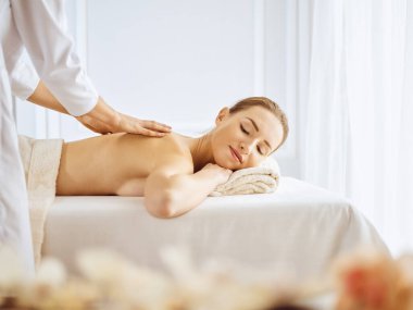 Güzel bir kadın kapalı gözlerle sırt masajından hoşlanıyor. Spa tedavisi kavramı