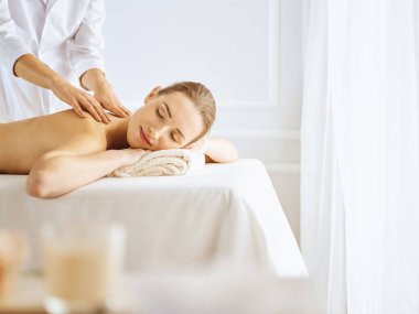 Güzel bir kadın kapalı gözlerle sırt masajından hoşlanıyor. Spa tedavisi kavramı