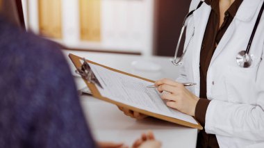 Doktor ve hasta güneşli klinikte otururken sağlık muayenesini tartışıyorlar. Hastanede mükemmel bir tıbbi hizmet.