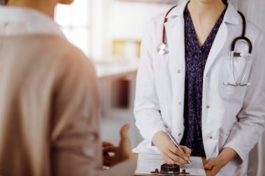 Doktor ve hasta güneşli klinikte otururken sağlık muayenesini tartışıyorlar. Hastanede mükemmel bir tıbbi hizmet.