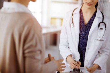 Doktor ve hasta güneşli klinikte otururken sağlık muayenesini tartışıyorlar. Hastanede mükemmel bir tıbbi hizmet.