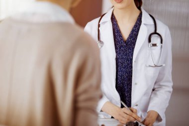 Doktor ve hasta güneşli klinikte otururken sağlık muayenesini tartışıyorlar. Hastanede mükemmel bir tıbbi hizmet.