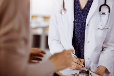 Doktor ve hasta güneşli klinikte otururken sağlık muayenesini tartışıyorlar. Hastanede mükemmel bir tıbbi hizmet.