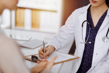 Doktor ve hasta güneşli klinikte otururken sağlık muayenesini tartışıyorlar. Hastanede mükemmel bir tıbbi hizmet.