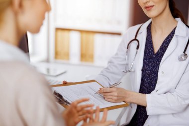 Doktor ve hasta güneşli klinikte otururken sağlık muayenesini tartışıyorlar. Hastanede mükemmel bir tıbbi hizmet.
