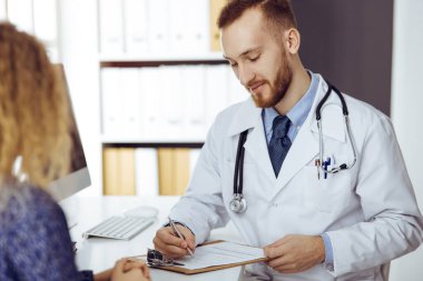 Dost canlısı kızıl sakallı doktor ve hasta kadın güneşli klinikte otururken sağlık muayenesini tartışıyorlar. Tıp konsepti