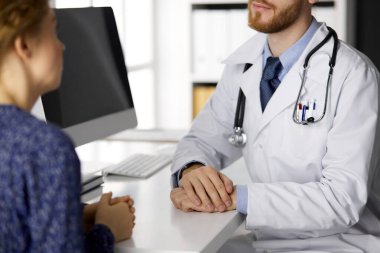 Dost canlısı kızıl sakallı doktor ve hasta kadın güneşli klinikte otururken sağlık muayenesini tartışıyorlar. Tıp konsepti