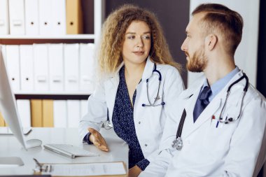 Kızıl sakallı doktor ve bayan meslektaşı güncel hastalık terapisini güneşli klinikte çalışırken tartışıyorlar. Tıpta takım çalışması