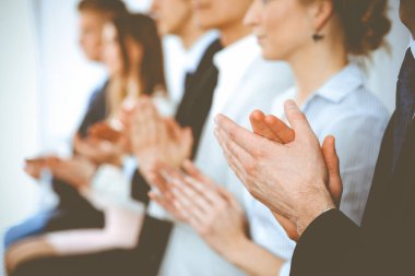 Business people clapping and applause at meeting or conference, close-up of hands. Group of unknown businessmen and women in modern white office. Success teamwork or corporate coaching concept clipart