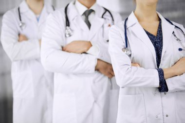 Doktorlar klinikte kollarını kavuşturmuş bir takım gibi duruyorlar. Tıbbi yardım, sigorta ve tıp konsepti