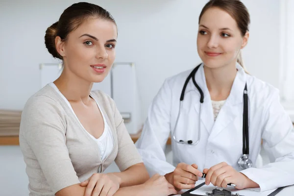 El médico y el paciente están sentados y discutiendo los resultados del examen de salud en el consultorio clínico. Salud, medicina y conceptos de buenas noticias — Foto de Stock