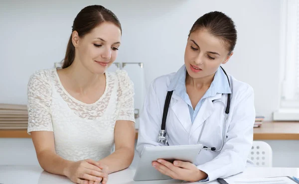 Γιατρός και ασθενής κάθονται και συζητούν τα αποτελέσματα των εξετάσεων υγείας κατά τη χρήση του υπολογιστή tablet. Ιατροφαρμακευτική περίθαλψη, ιατρική και καλές ειδήσεις — Φωτογραφία Αρχείου