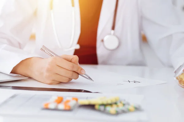 Mulher-médico desconhecido preenche formulário de prescrição em quarto ensolarado, close-up — Fotografia de Stock