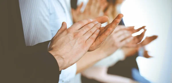 Business people clapping and applause at meeting or conference, close-up of hands. Group of unknown businessmen and women in modern white office. Success teamwork or corporate coaching concept