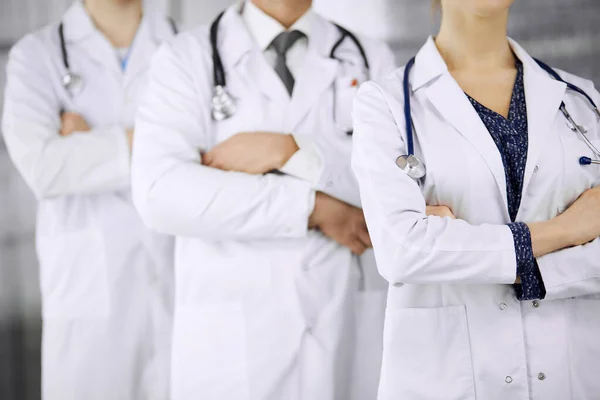 Doktoři stojí jako tým se zkříženýma rukama na klinice. Lékařská pomoc, pojetí pojištění a medicíny — Stock fotografie