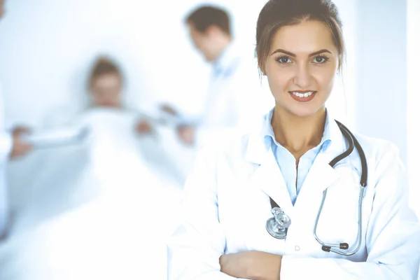 Female doctor smiling on the background with patient in the bed and two doctors Royalty Free Stock Images