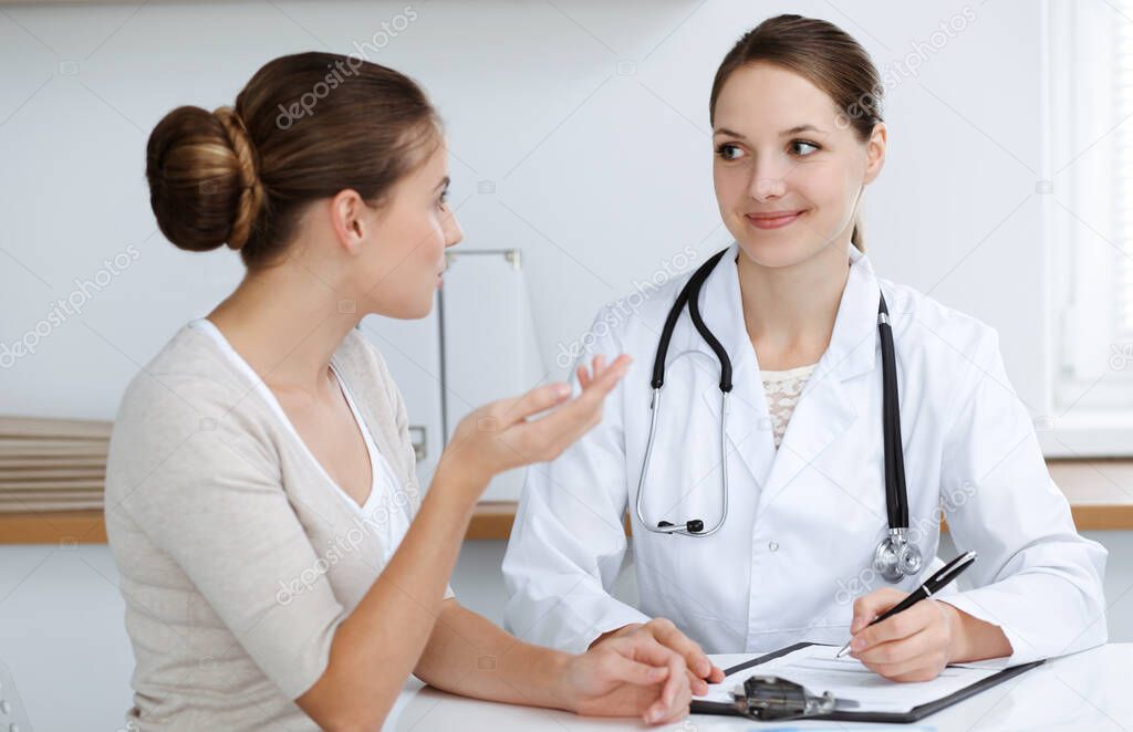 Doctor and patient are sitting and discussing health examination results in clinic office. Health care, medicine and good news concepts