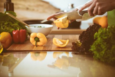 Mutfakta pişen bilinmeyen insan elleri. Sarı dolma biber dilimleyen kadın. Sağlıklı yemek ve vejetaryen gıda konsepti.