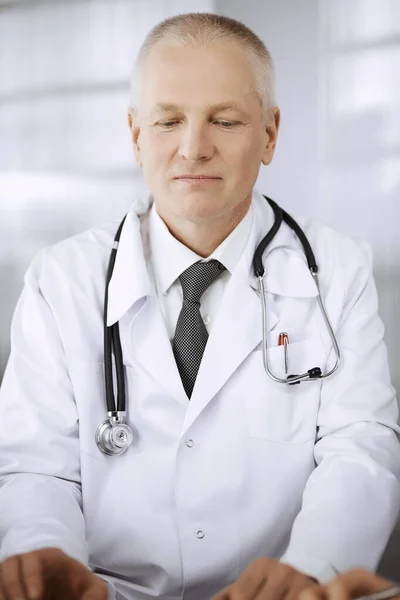 Doctors colleagues and elderly therapist discussing current disease therapy while sitting at working place in clinic. Teamwork in hospital. Medicine and healthcare concept — Stock Photo, Image