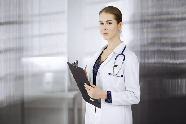 Allegro dottore donna in piedi in clinica. Ritratto di amichevole sorridente medico donna. Servizio medico perfetto in ospedale. Concetto di medicina — Foto Stock