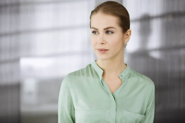 Schöne erwachsene Geschäftsfrau in grüner Bluse, die gerade im Büro steht. Kopfschuss oder Porträt — Stockfoto