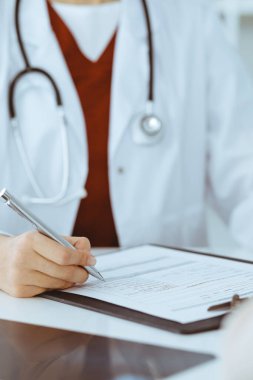 Bilinmeyen kadın-doktor hastaya danışmanlık yaparken başvuru formu dolduruyor. Tıp konsepti