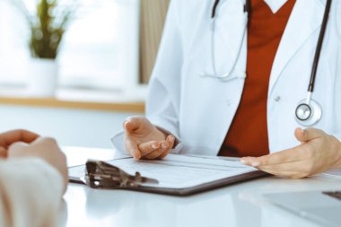 Bilinmeyen kadın doktor ve hasta klinikteki masada otururken bir şey tartışıyorlar, yakın plan. Tıp konsepti