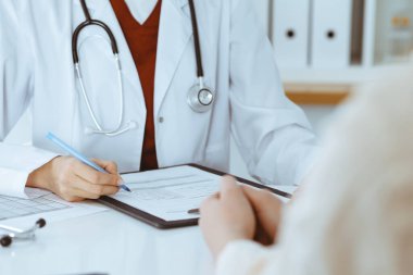 Bilinmeyen kadın-doktor hastaya danışmanlık yaparken başvuru formu dolduruyor. Tıp konsepti