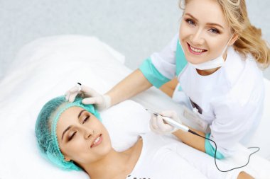 Kadın yüzüne kaş dövmesi yapan profesyonel bir güzellik uzmanı. Güzellik salonunda kalıcı kaş makyajı, yakın çekim. Kozmetoloji tedavisi