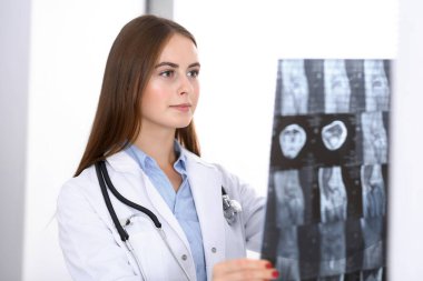 Doktor kadın hastanenin penceresinin yanında dikilirken röntgen filmini inceliyor. Cerrah ya da ortopedist. Tıp ve sağlık hizmetleri kavramı