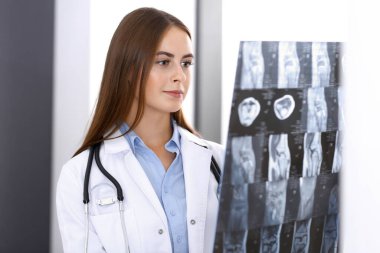 Doktor kadın hastanenin penceresinin yanında dikilirken röntgen filmini inceliyor. Cerrah ya da ortopedist. Tıp ve sağlık hizmetleri kavramı