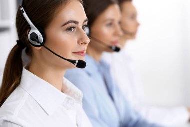 Merkezi ara. Bir grup operatör iş başında. Kulaklıklı güzel iş kadınına odaklan.