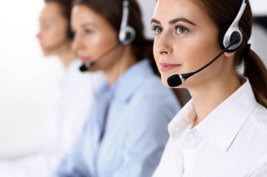 Merkezi ara. Bir grup operatör iş başında. Kulaklıklı güzel iş kadınına odaklan.