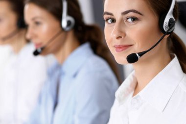 Merkezi ara. Bir grup operatör iş başında. Kulaklıklı güzel iş kadınına odaklan.