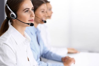 Merkezi ara. Bir grup operatör iş başında. Kulaklıklı güzel iş kadınına odaklan.