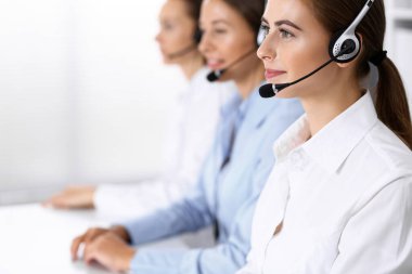 Merkezi ara. Bir grup operatör iş başında. Kulaklıklı güzel iş kadınına odaklan.