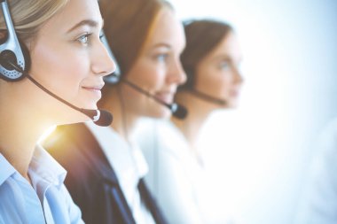 Kulaklıklı, güler yüzlü iş kadını müşterilere danışıyor. Sunny Office 'de çalışan çeşitli telefon operatörleri. Çağrı merkezi ve iş adamları kavramı.