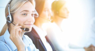 Kulaklıklı, güler yüzlü iş kadını müşterilere danışıyor. Sunny Office 'de çalışan çeşitli telefon operatörleri. Çağrı merkezi ve iş adamları kavramı.