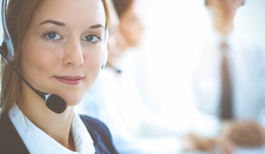 Kulaklıklı, güler yüzlü iş kadını müşterilere danışıyor. Sunny Office 'de çalışan çeşitli telefon operatörleri. Çağrı merkezi ve iş adamları kavramı.