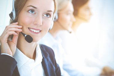 Kulaklıklı, güler yüzlü iş kadını müşterilere danışıyor. Sunny Office 'de çalışan çeşitli telefon operatörleri. Çağrı merkezi ve iş adamları kavramı.
